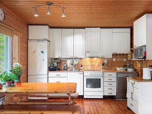 Una cocina con armarios de madera, un refrigerador, una estufa y un microondas.
