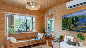 Una habitación acogedora con techo de madera, un sofá, una mesita, un espejo y un cuadro de un paisaje.