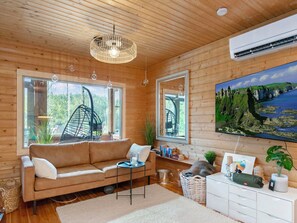 A cozy room with a wooden ceiling, a sofa, a small table, a mirror, and a painting of a landscape.