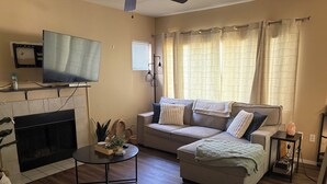 A living room with a fireplace, a sofa, a coffee table, and a television. - Charming condo in Downtown Gilbert (Gilbert)