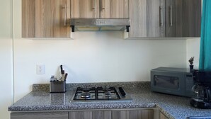 A kitchen with wooden cabinets, a gas stove, a microwave, and a coffee maker.