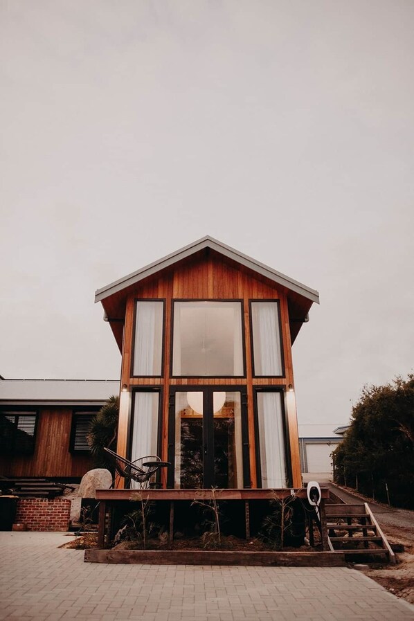 Una casa moderna de madera con ventanas grandes y un porche.