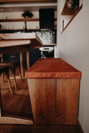 A wooden bench with a slatted design, positioned in a room with a kitchen in the background. - View Street Studios - Yarri (Albany)