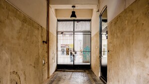 A narrow hallway with a tiled floor, a metal gate, and a door on the right. - Old Town Harmony Studio (Poznań)