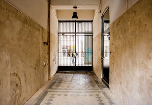 A narrow hallway with a tiled floor, a metal gate, and a door on the right. - Old Town Harmony Studio (Poznań)