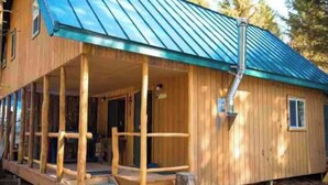 A wooden cabin with a porch, a metal roof, and a chimney. - Lovely 1-bedroom cabin in Anchor Point perfect for a cozy getaway (Anchor Point)