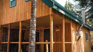 A wooden cabin with a porch, a chimney, and a window. - Lovely 1-bedroom cabin in Anchor Point perfect for a cozy getaway (Anchor Point)