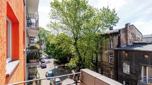 Vista callejera con edificios, un árbol y coches estacionados.