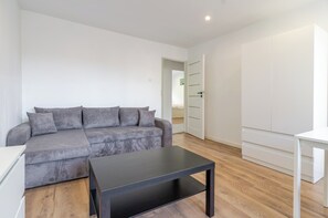 A modern living room with a grey sofa, a black coffee table, and a white cabinet.