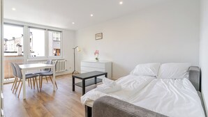 Una habitación moderna y luminosa con cama, escritorio y silla, que ofrece vistas amplias a través de grandes ventanales.