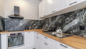 Une cuisine moderne avec un dosseret en marbre, des appareils en acier inoxydable et des plans de travail en bois.