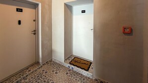 Un couloir avec deux portes portant les inscriptions « M4 » et « M5 », un paillasson et un détecteur d’incendie.