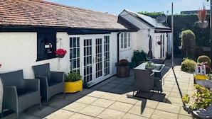 Une terrasse avec des meubles d’extérieur, un pot de fleurs jaune et des plantes en pot.