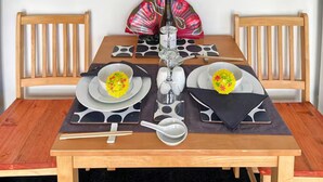 Une table à manger dressée avec des assiettes, des bols, des baguettes, une bouteille et un éventail.