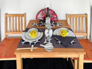 Et spisebord dækket med tallerkener, skåle, spisepinde, en flaske og en vifte.