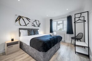 Un dormitorio moderno con cama, mesita de noche y una silla.