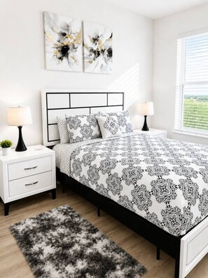 A bedroom with a bed, nightstands, lamps, a rug, and artwork on the wall. - Upscale 1BR • Downtown • Steps to Bathhouse Row (Hot Springs)