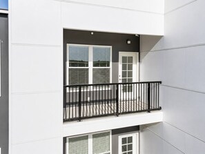 A multi-story building with a balcony featuring a black metal railing. - Upscale 1BR • Downtown • Steps to Bathhouse Row (Hot Springs)