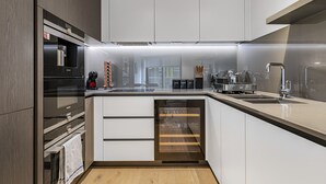 Een moderne keuken met een inbouwoven, een koffieapparaat en een wijnkoeler.