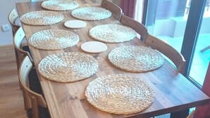 Una mesa de comedor de madera con individuales tejidos y sillas.