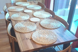 A wooden dining table with woven placemats and chairs.