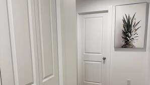 Ein Flur mit weißen Türen, Holzboden und einem gerahmten Bild an der Wand.