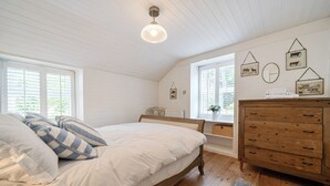 Ett sovrum med en säng, en byrå och fönster.