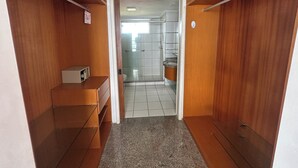 Ein schmaler Korridor mit Holzwänden und Fliesenboden, der zu einem Badezimmer mit Dusche und Toilette führt.