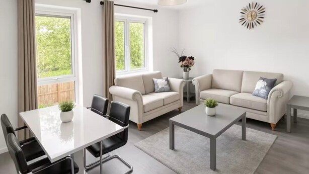 Ein modernes Wohnzimmer mit Esstisch, zwei Sofas, einem Couchtisch und einer Wanddekoration.