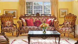 A room with a tufted sofa set, two ornate armchairs, a glass coffee table, and two framed landscape paintings on the walls. - Villa Sleeps up to 17 - Hot Tub, Garden, Parking (Pinner)