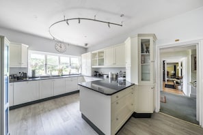 Una cocina amplia con armarios blancos, una isla central y un ventanal que proporciona luz natural.