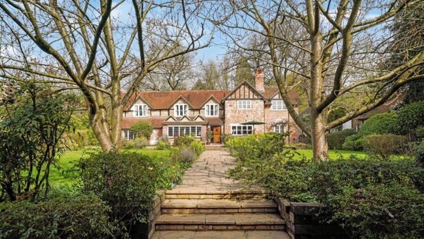 A traditional house with a stone pathway leading to the entrance, surrounded by lush greenery and trees. - Villa Sleeps up to 17 - Hot Tub, Garden, Parking (Pinner)