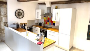 Een keuken met witte kastjes, een houten aanrechtblad, een ingebouwde oven en een kleurrijke spatwand.