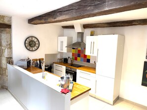 Eine Küche mit weißen Schränken, einer Holzarbeitsplatte, einem eingebauten Backofen und einer farbenfrohen Spritzschutzwand.