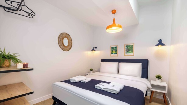 A neatly made bed with folded towels, a bedside table with a plant, a wall-mounted mirror, and a hanging light fixture. - Panoramic Bosphorus View Terrace At Monnas Suite (Istanbul)