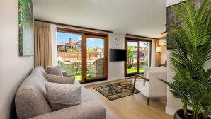 A living room with a sofa, armchairs, a TV, and a large window with a view of a garden. - Huge Balcony Taksim Rooftop Apt At Monnas Suite (Istanbul)