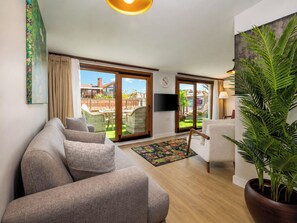 A living room with a sofa, armchairs, a TV, and a large window with a view of a garden. - Huge Balcony Taksim Rooftop Apt At Monnas Suite (Istanbul)