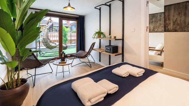 A hotel room with a bed, two chairs, a small table with a plant, a heater, and a view of the outside. - Huge Balcony Taksim Rooftop Apt At Monnas Suite (Istanbul)