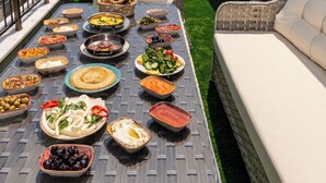 A dining table with various dishes, a wicker chair, and a white sofa. - Huge Balcony Taksim Rooftop Apt At Monnas Suite (Istanbul)