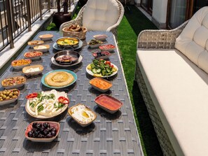 A dining table with various dishes, a wicker chair, and a white sofa. - Huge Balcony Taksim Rooftop Apt At Monnas Suite (Istanbul)