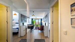 Ein Hotelzimmer mit Bett, Schreibtisch, Stuhl, Esstisch und Blick auf die Stadt.