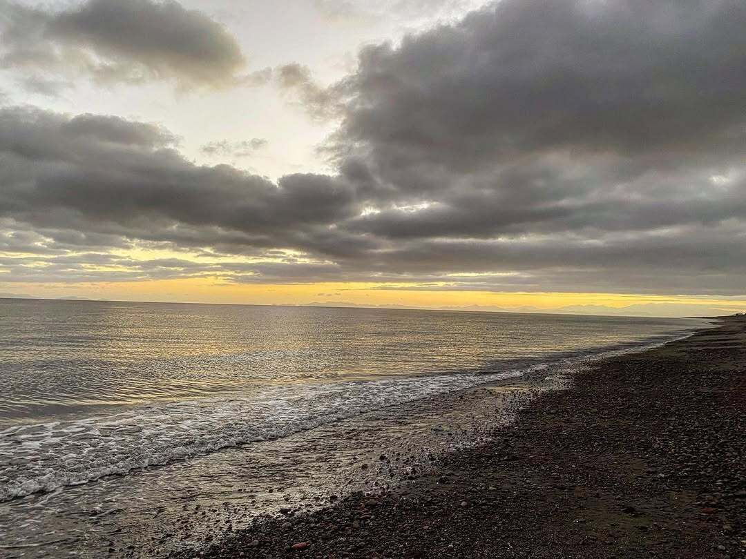Una playa con costa rocosa y cielo nublado.