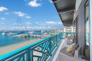 Ein Balkon mit Blick auf eine Marina, Gartenmöbel und einem klaren Himmel.