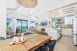 Eine moderne Küche mit weißen Schränken, einem Holztisch und einem großen Fenster mit Blick auf eine schöne Landschaft.