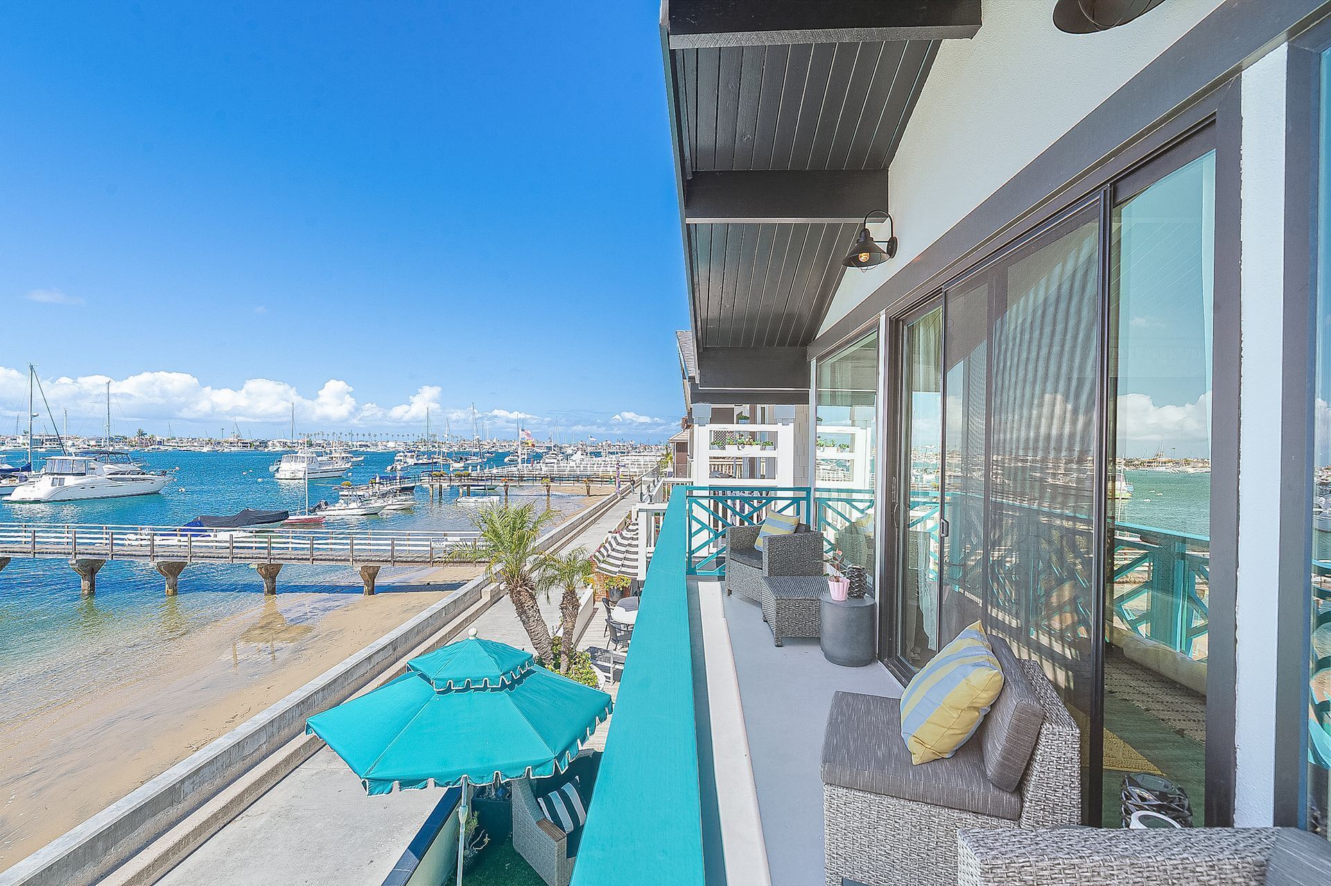 Ein Balkon mit Blick auf eine Marina, Gartenmöbel und ein großes Fenster.