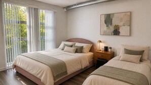 Et soveværelse med to senge, et natbord, en lampe og et maleri på væggen.
