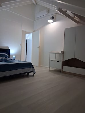 Ein Schlafzimmer mit Bett, Kleiderschrank, Schreibtisch und Deckenventilator.