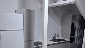 Una cucina compatta con elettrodomestici bianchi, una panca di legno e una piccola isola con lavello.