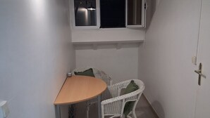 Una stanza modesta con un tavolo, una sedia, una finestra vista e una porta.