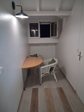 Ein kleiner Raum mit Tisch, Stuhl, Fenster und Tür.